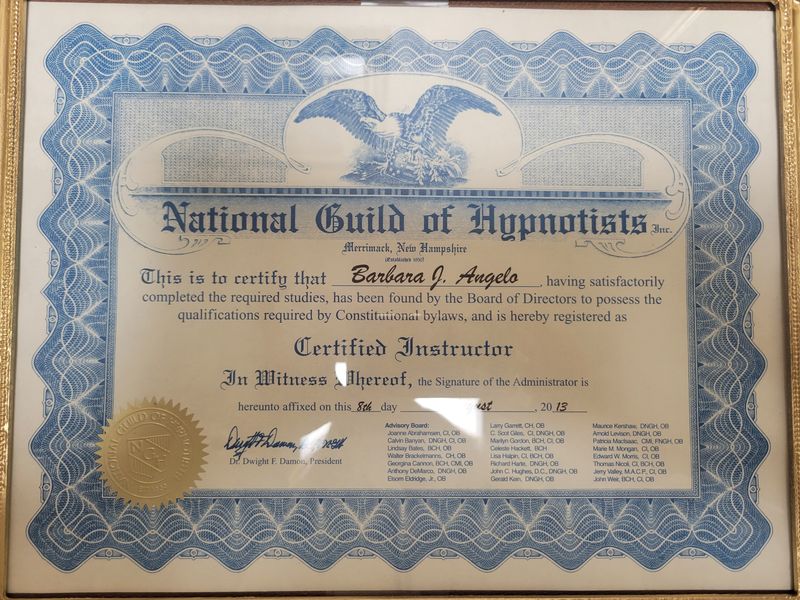 The image displays a framed certificate from the National Guild of Hypnotists. It includes decorative elements, such as a blue border and an eagle design at the top. The certificate certifies an individual as a "Certified Instructor" and confirms that they have completed the necessary studies as recognized by the Guild's Board of Directors. The document features signatures and a seal, indicating its authenticity, and is dated.