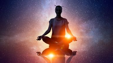 The image depicts a silhouette of a person meditating in a lotus position. The background features a starry night sky with a colorful cosmic scene, including stars and nebulas. The figure appears to be radiating light, creating an ethereal effect against the dark space backdrop. The overall tone suggests themes of tranquility, spirituality, and cosmic exploration.