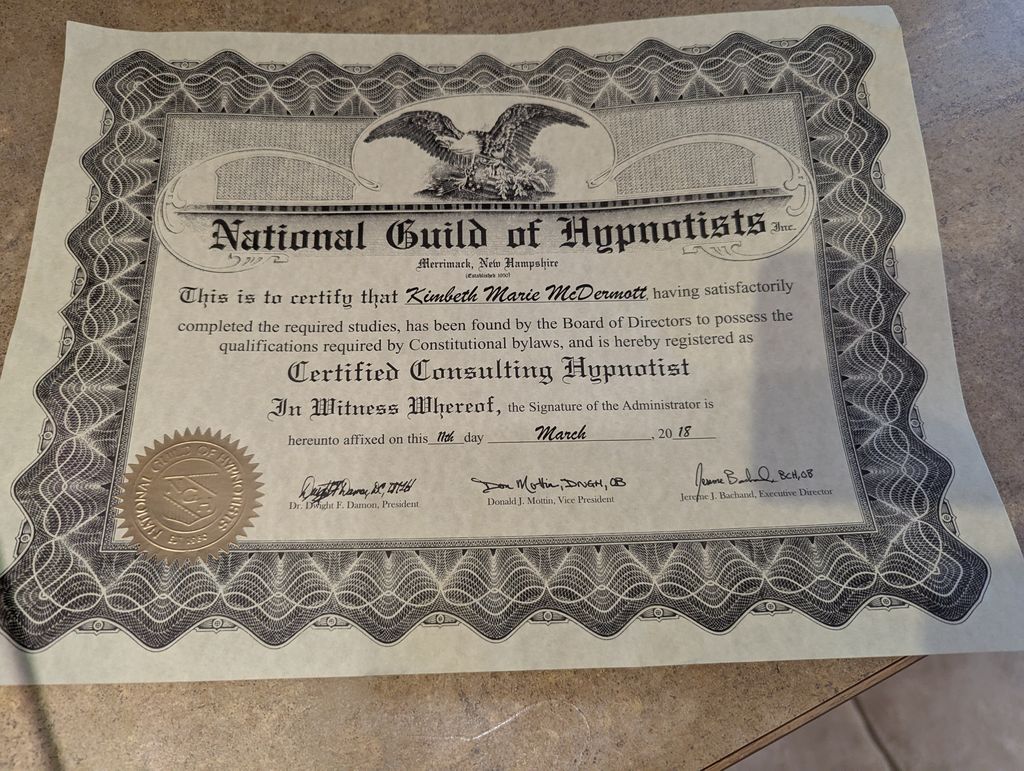The image shows a certificate from the National Guild of Hypnotists, issued in New Hampshire. It certifies that an individual has satisfactorily completed the required studies and is registered as a Certified Consulting Hypnotist. The certificate features decorative elements, including an eagle emblem and an official seal. It is dated March 2018 and includes signatures from officials of the organization.