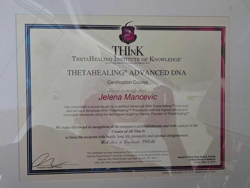 The image depicts a certificate from the ThetaHealing Institute of Knowledge, indicating that the recipient has completed a course in Advanced DNA ThetaHealing. The certificate features decorative elements, including a logo at the top, a border, and signatures that affirm the accomplishment. It includes a message of recognition for the recipient's achievements and a prayer for their well-being. The document is presented in a frame or holder, suggesting it is intended for display.