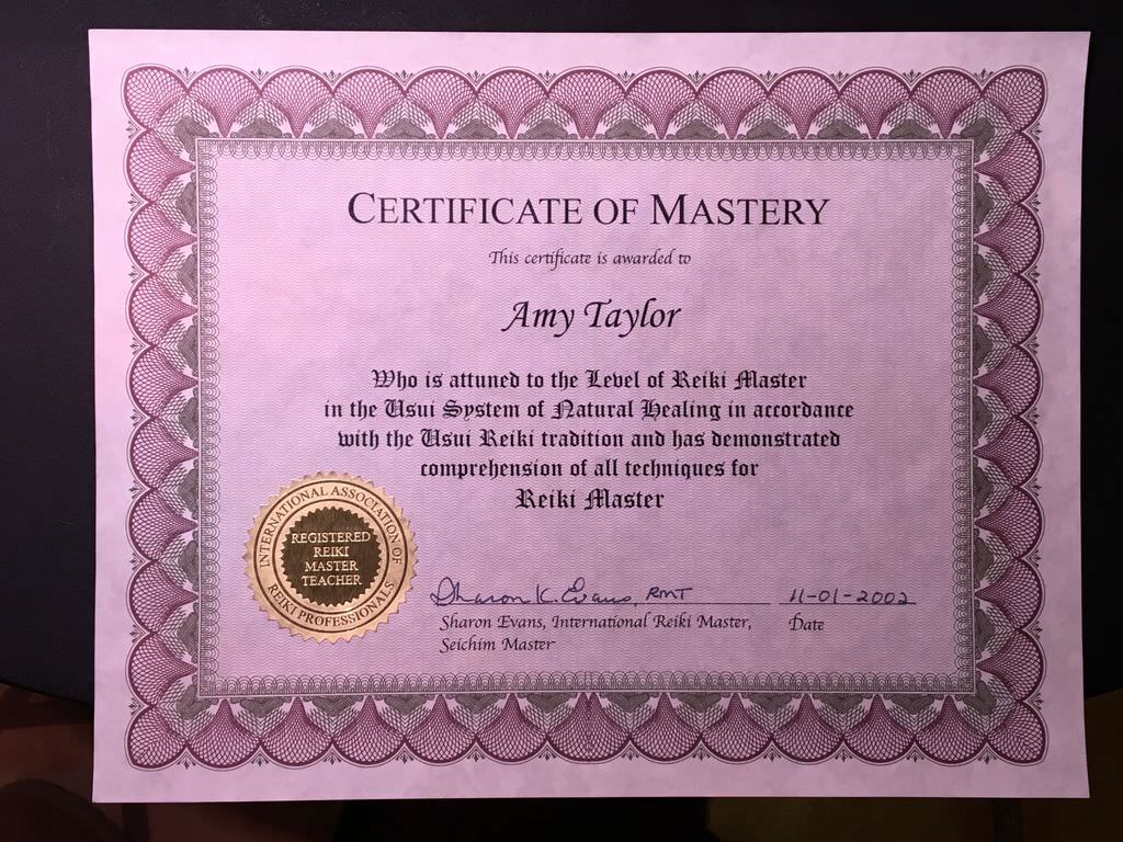 The image is a certificate titled "Certificate of Mastery." It features a decorative border with a light purple background and includes text that awards the certificate to an individual. The certificate states that the recipient is recognized as a Reiki Master in the Usui System of Natural Healing. It also includes a seal indicating a registered Reiki Master Teacher and is signed by an individual along with a date. The overall layout is formal and celebratory.