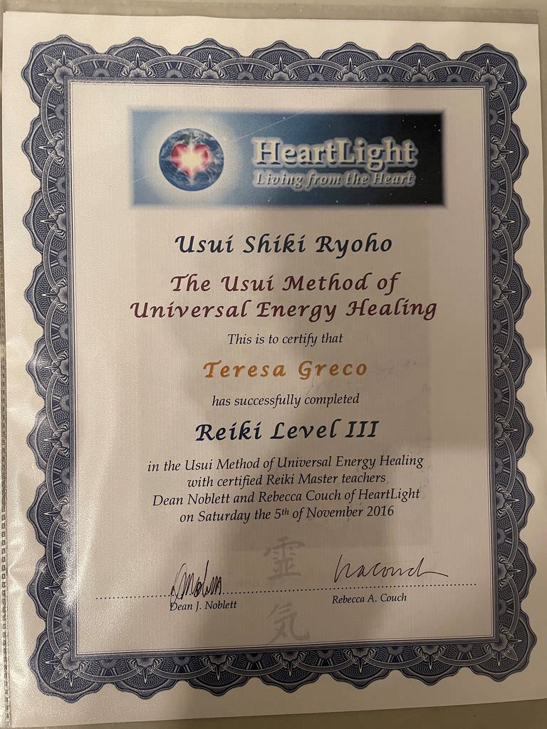 The image shows a certificate for completing Reiki Level III, specifically focusing on Usui Shiki Ryoho, which is a method of universal energy healing. The certificate is awarded to an individual named Teresa Greco. It features a logo at the top, which includes the words "HeartLight" and "Living from the Heart." The certificate is signed by two individuals, Dean J. Noblett and Rebecca A. Couch, and it is dated November 5, 2016. The design includes decorative borders and an official look typical of a certification document.