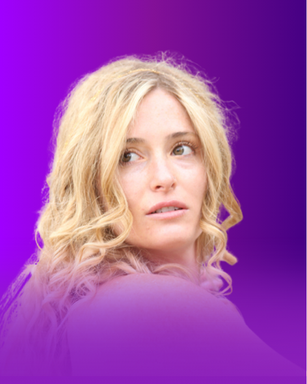The image features a woman with long, wavy blonde hair. She is looking over her shoulder with a thoughtful expression. The background is a gradient of purple shades, creating a vibrant and colorful backdrop.