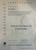 The image is of a certificate issued by a kinesiology program. It certifies that an individual named Diane Hudock has completed a minimum of 60 hours of instruction in various subjects related to kinesiology, including muscle testing and acupuncture touch. The certificate is titled "Touch for Health Synthesis" and includes the instructor's name, date, location, and the name of the issuing school. The design features a formal layout with text in both standard and stylized fonts.