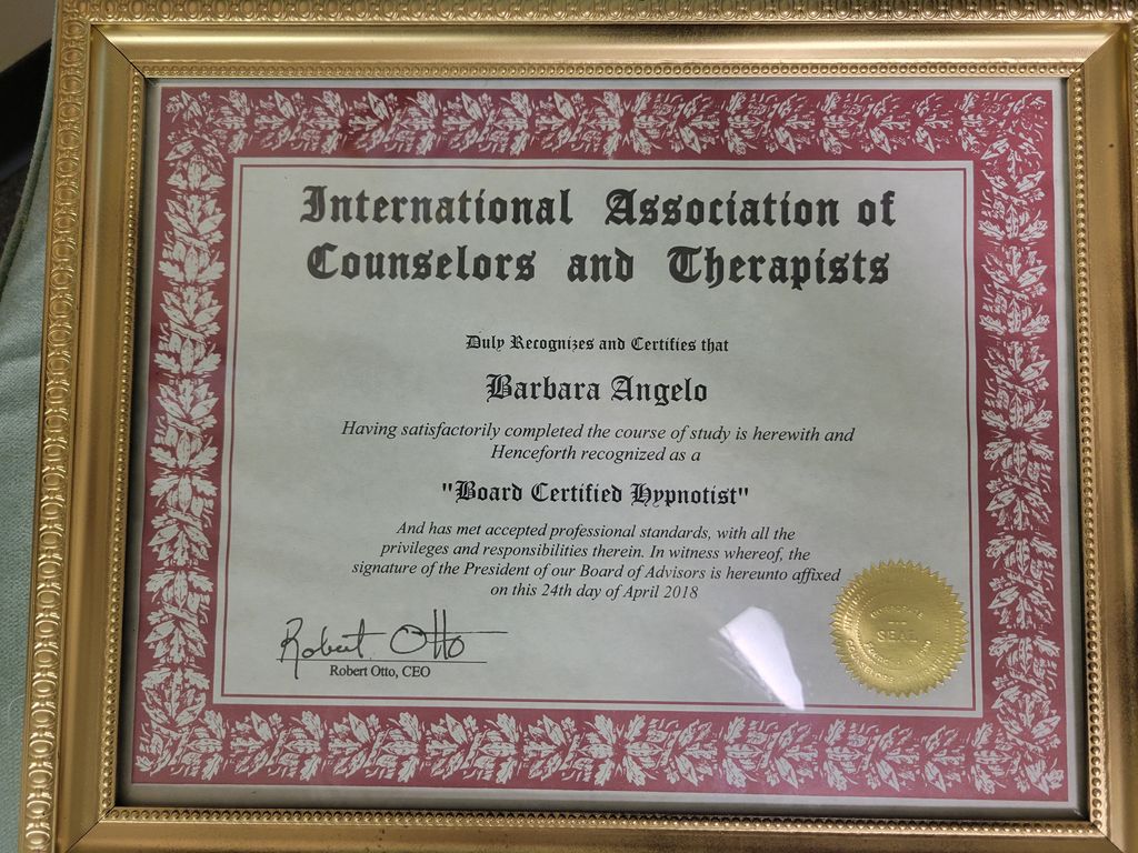 The image shows a framed certificate from the "International Association of Counselors and Therapists." The certificate states that an individual has satisfactorily completed a course of study and is recognized as a "Board Certified Hypnotist." It includes a signature and a seal, indicating official recognition, and is dated April 24, 2018. The frame features a decorative border.