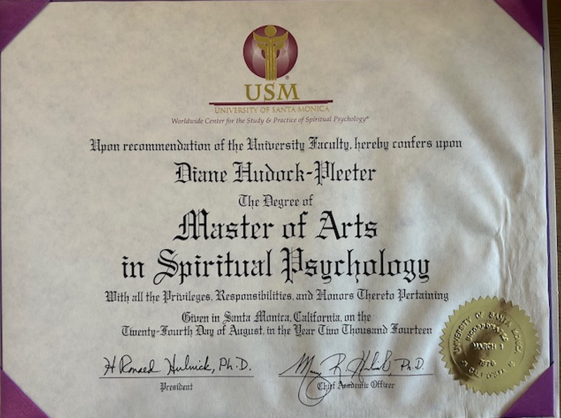 The image depicts a diploma from the University of Santa Monica (USM). It states that a degree, specifically a Master of Arts in Spiritual Psychology, has been conferred upon the individual. The document features formal language, the university's emblem, and signatures from the president and chief academic officer. Additionally, there is a seal indicating the authenticity of the diploma, along with the date it was issued. The overall presentation has a formal and ceremonial appearance.